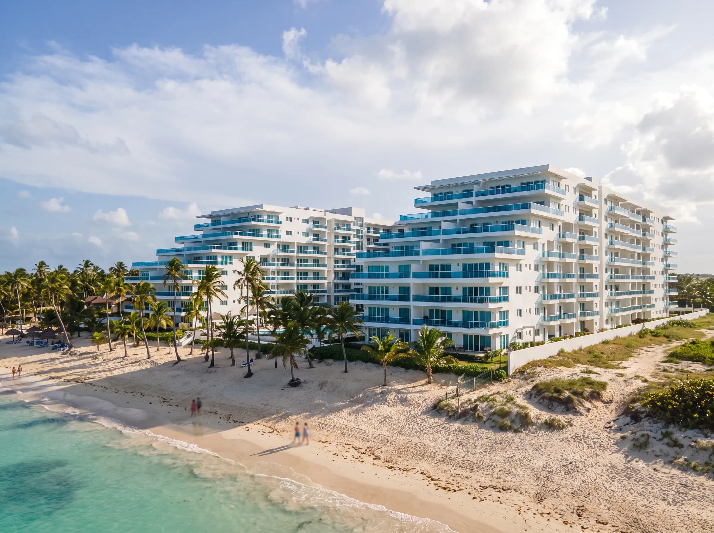 Modern residential complex beachfront in Punta Cana, with white buildings and blue glass balconies next to the beach