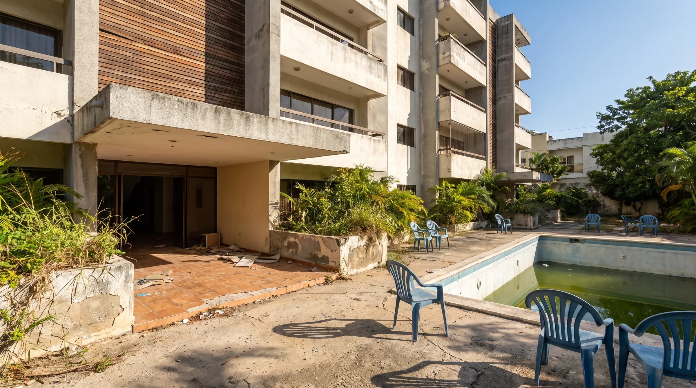 Edificio residencial moderno en Santiago con áreas comunes descuidadas, piscina sin mantenimiento y entrada deteriorada que simboliza los conflictos en condominios dominicanos