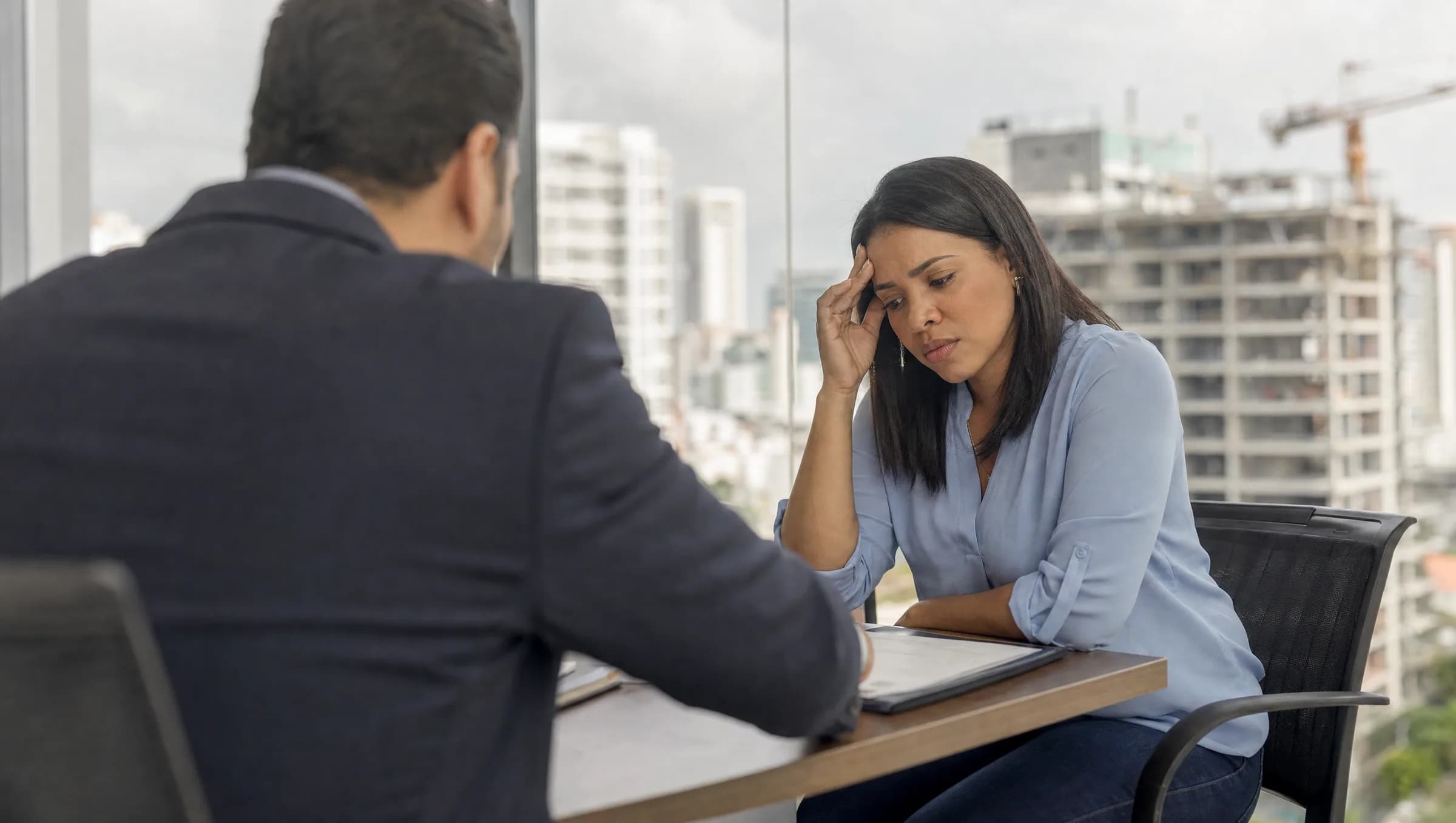 Mujer dominicana mostrando preocupación mientras revisa documentos de proyecto inmobiliario en oficina de Santo Domingo