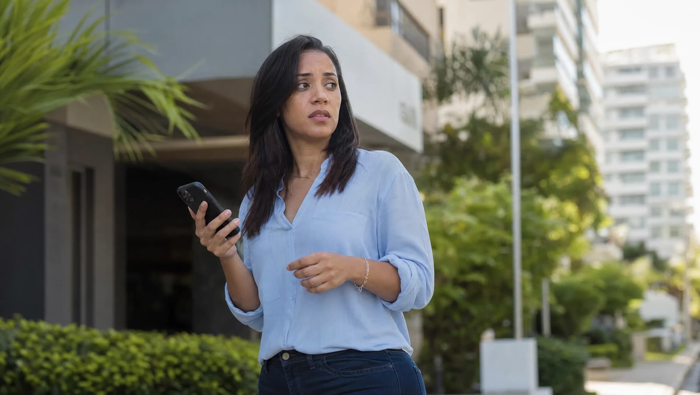 Mujer dominicana sosteniendo teléfono con múltiples chats de WhatsApp, mostrando ansiedad mientras busca agente inmobiliario en Piantini, Santo Domingo