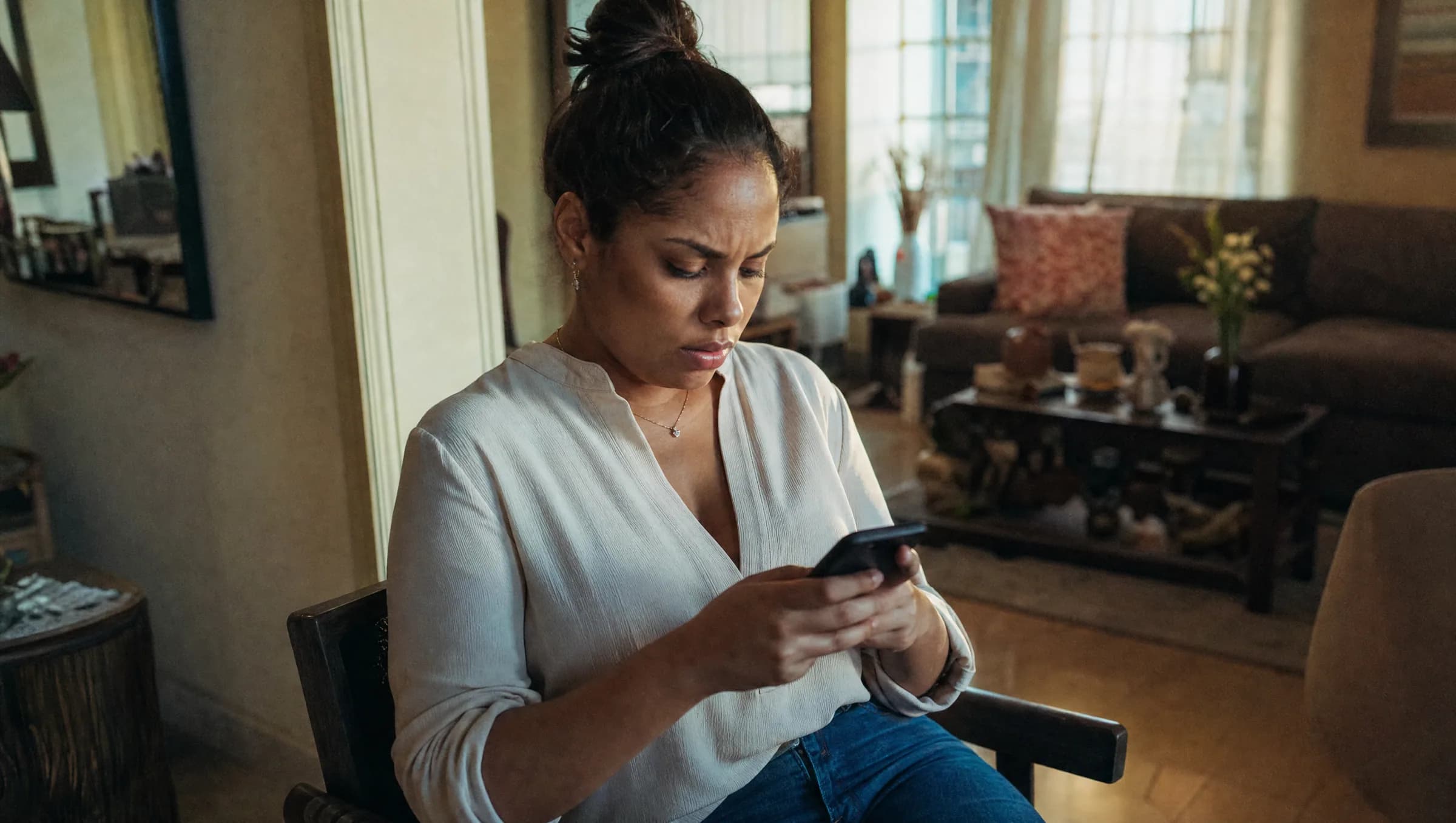 Mujer dominicana mirando preocupada su teléfono móvil en su apartamento en Santiago, después de realizar una transferencia bancaria