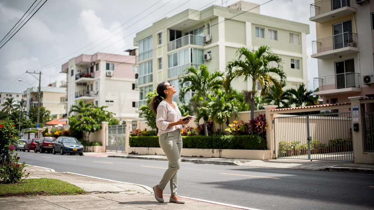 Mujer dominicana joven observando edificios residenciales en Santo Domingo mientras busca apartamento para comprar