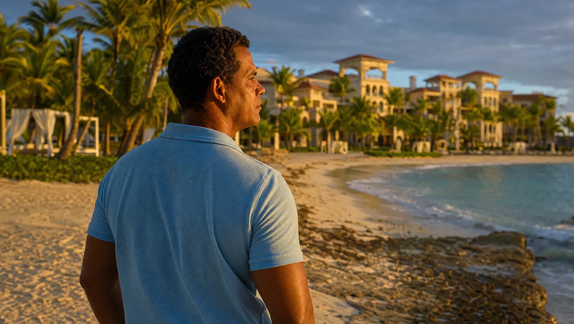 Hombre dominicano contemplando pensativo un complejo de resort en Punta Cana desde la playa, reflexionando sobre una decisión de inversión en tiempo compartido
